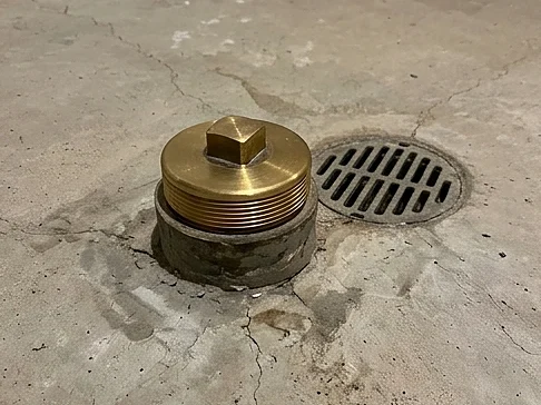 Sewer cleanout cap and floor drain in an older Twin Cities basement